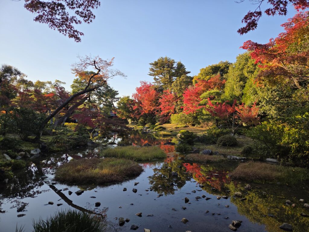 The elegant Japanese garden at Murin-an in Kyoto, featuring a flowing stream, open lawn, and the Higashiyama Mountains as borrowed scenery.