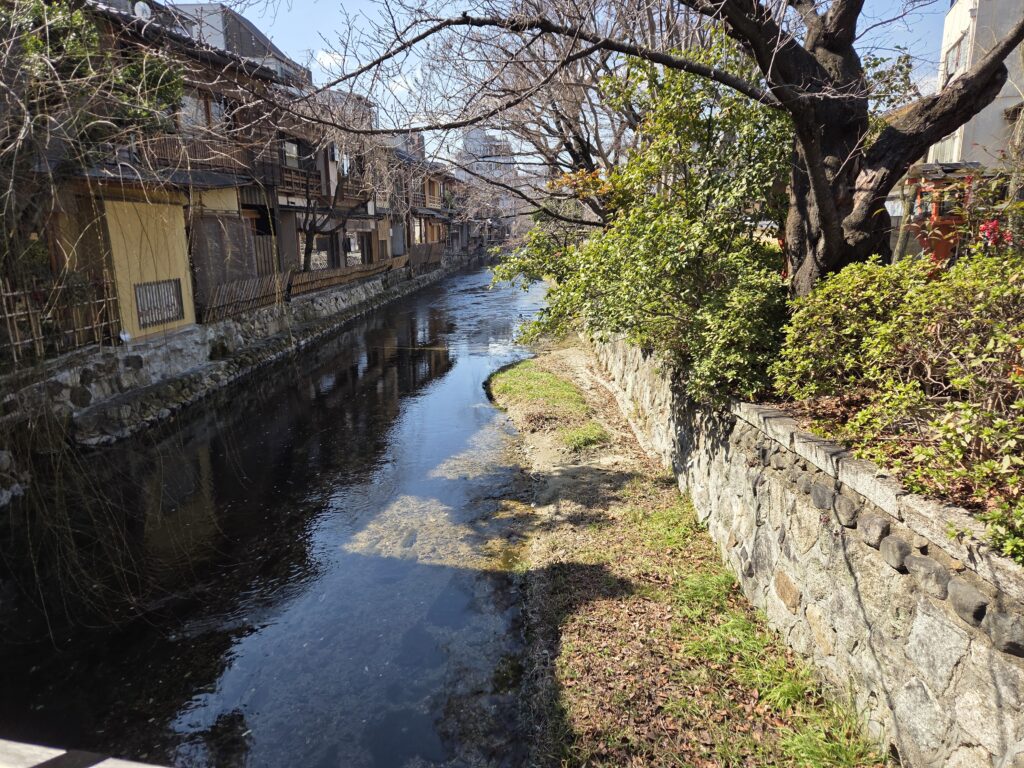 Traditional wooden machiya houses lining the Shirakawa Canal in Gion, Kyoto, with picturesque stone-paved streets and timeless atmosphere.