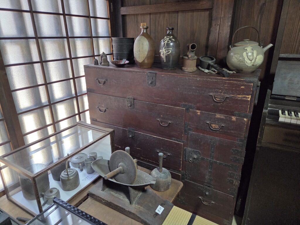 Traditional household tools, pottery, and a wooden chest displayed inside Takagi Residence in Imai-cho, Nara