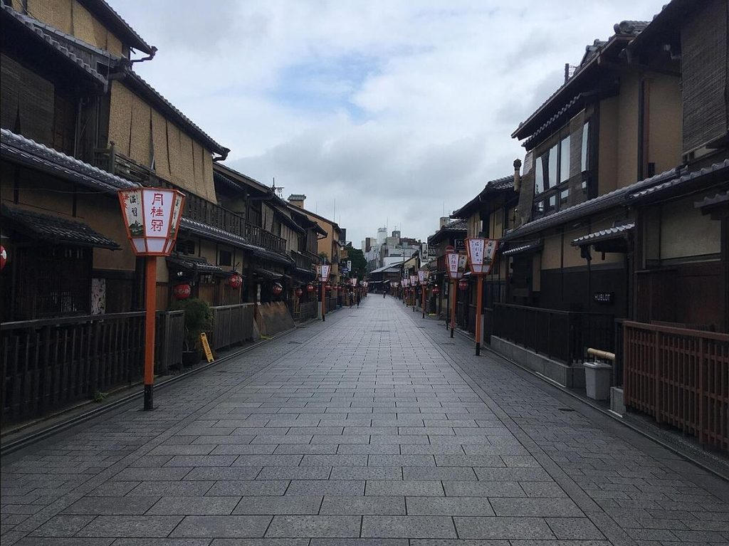 Empty stone-paved Hanamikoji Street lined with traditional wooden machiya buildings and lanterns in Gion, Kyoto